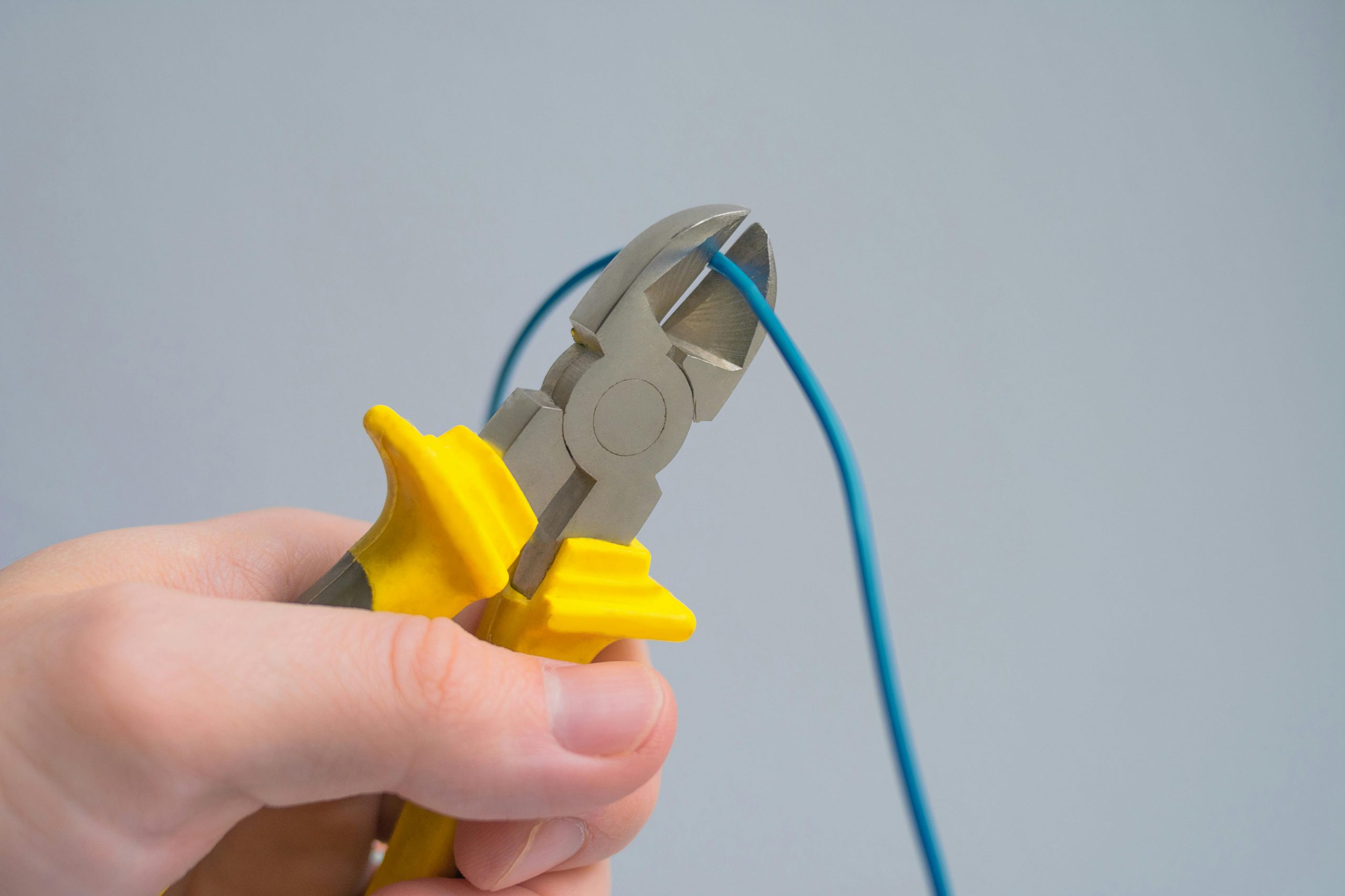 close-up of hand cutting a blue cable with pliers