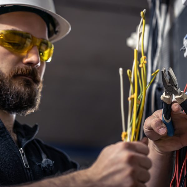 electrician wearing safety gear while wiring an electrical switchboard